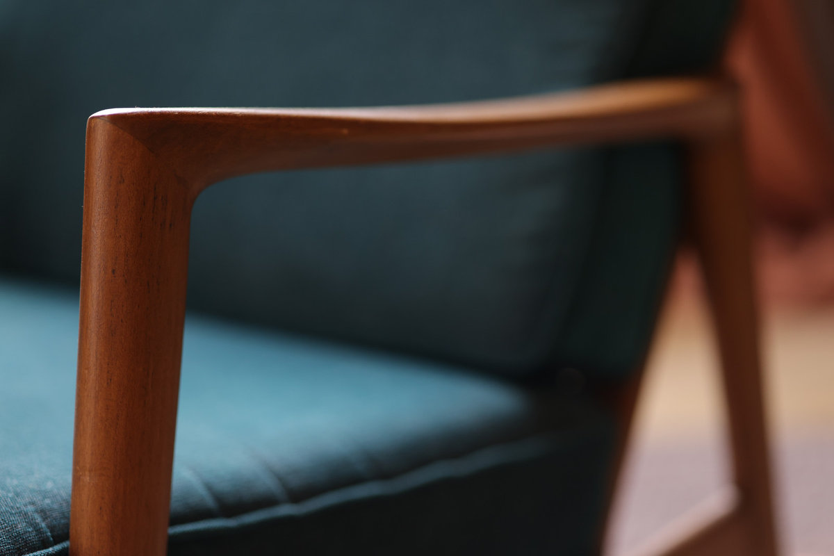 Accoudoir en bois et velours bleu canard d’un fauteuil